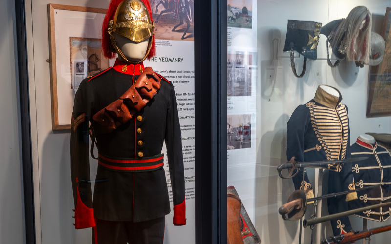 Display cabinet with mannequin dressed in navy blue uniform with red trim and gold helmet with red plume