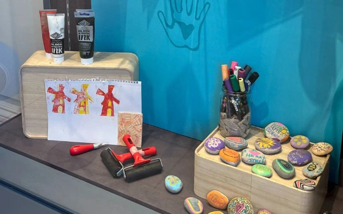 Decorated stones and arrts and crafts materials on display in glass cabinet