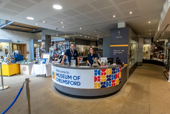 People smiling and standing beind front desk at the Museum of Chelmsford